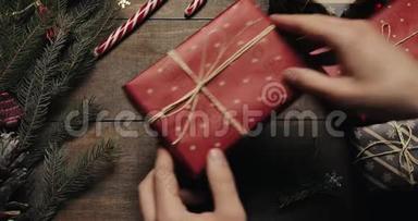 男子手把礼品盒用<strong>装饰线</strong>绑好后用红纸包在木桌上，准备